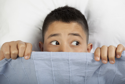 Scared boy hiding in bed
